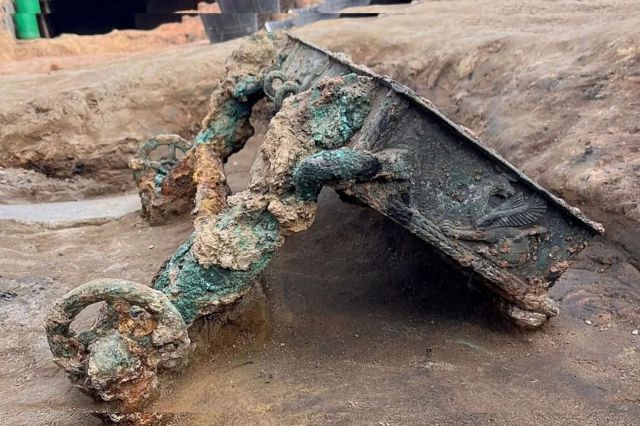 An ancient chariot partially buried in sand.