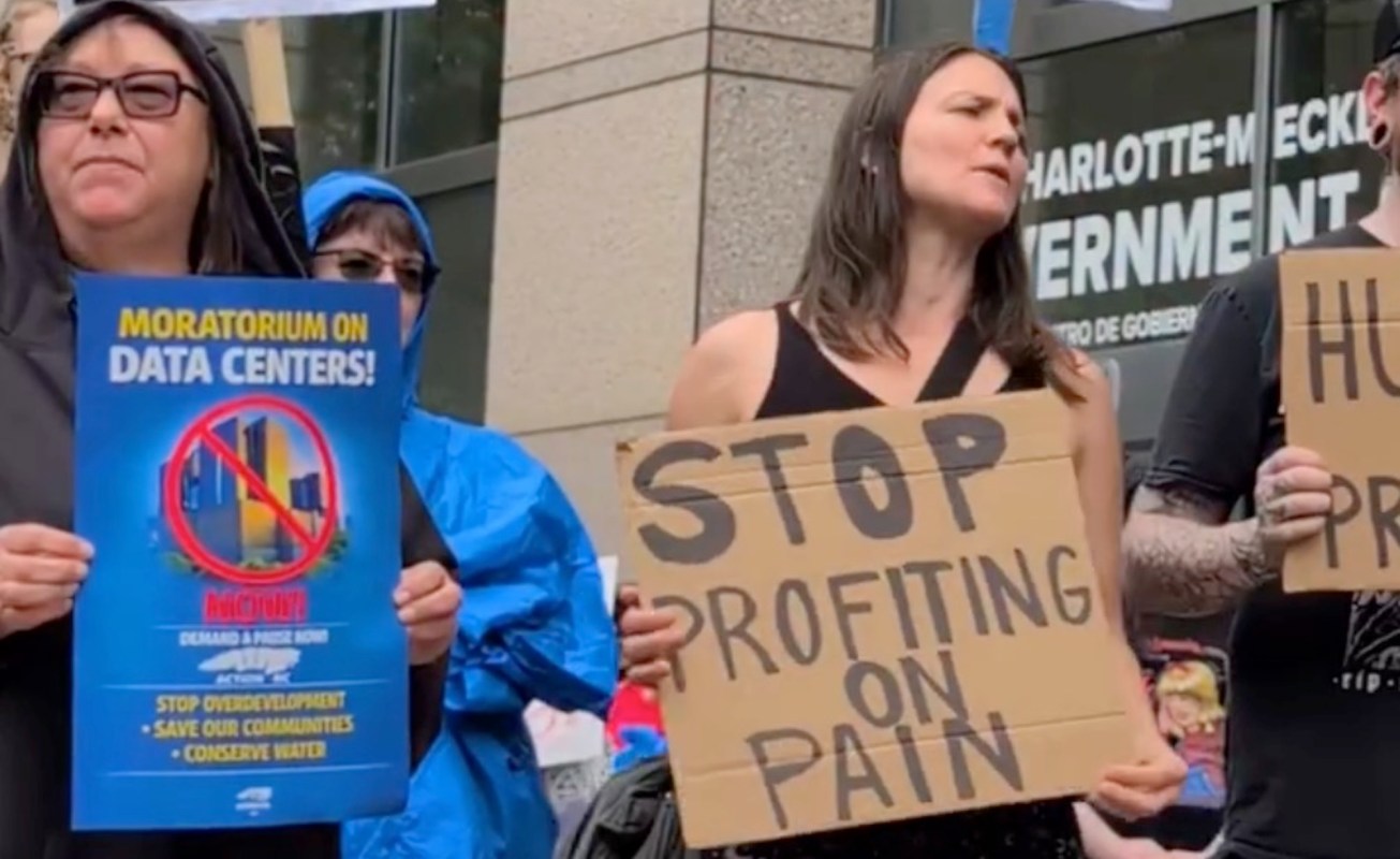 A group of protesters holds signs demanding a moratorium on data centers and opposing profit from pain.