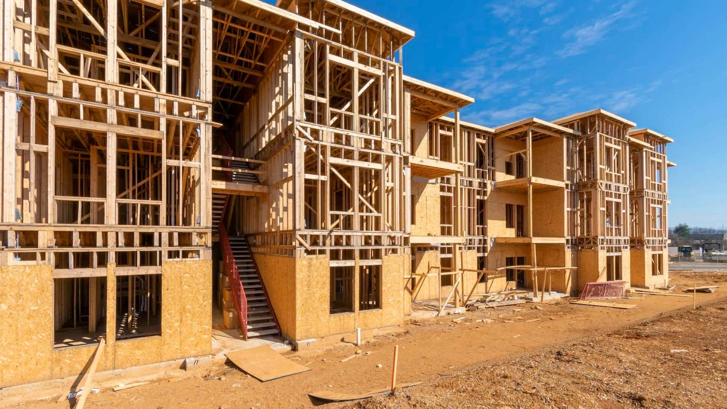 A construction site with partially completed wooden apartment buildings.