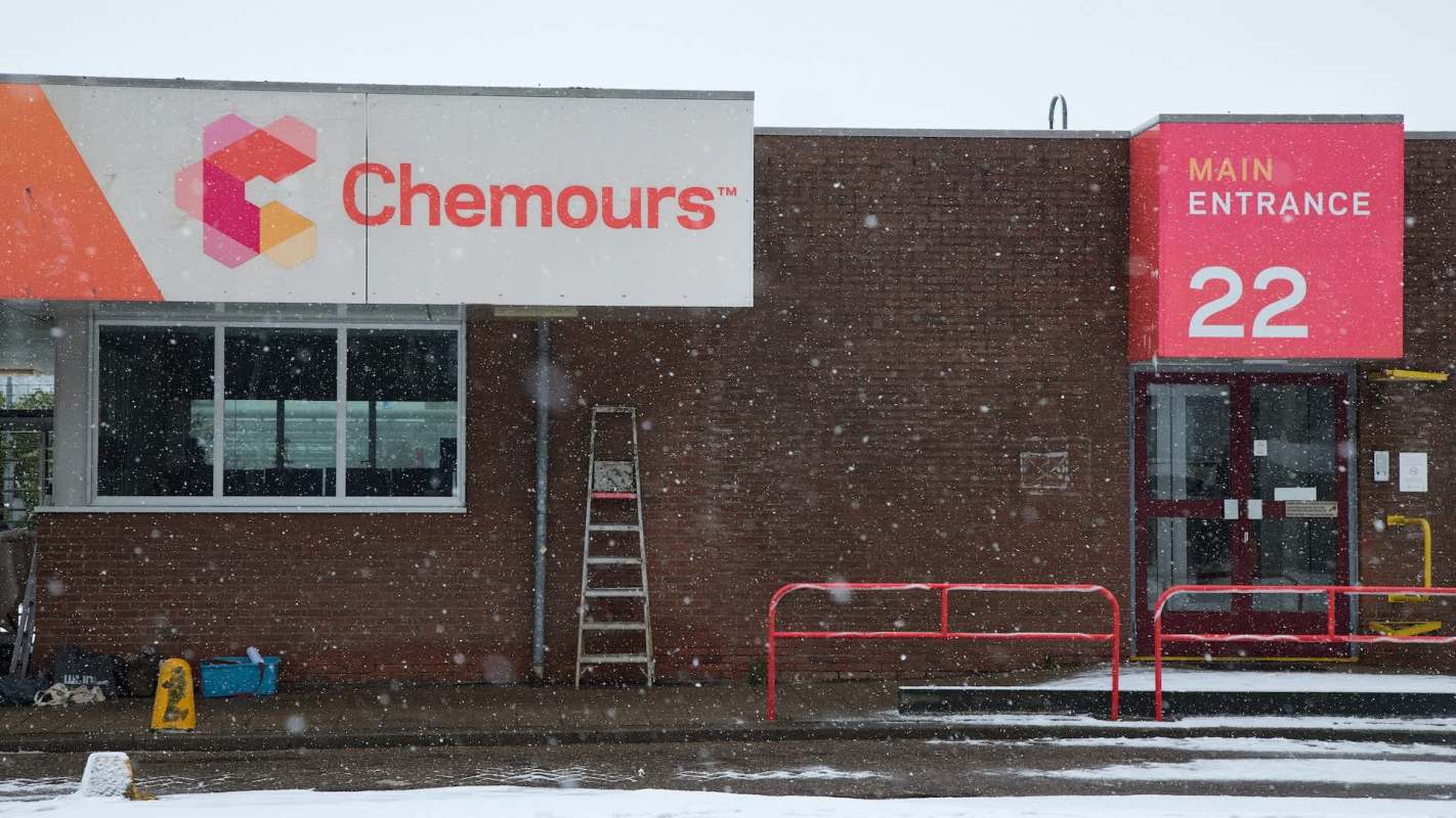 A snowy scene featuring the entrance of a building with a Chemours sign and a red main entrance marker.