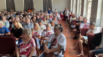 A large group of people, some wearing anti-data center shirts, attending a town hall.