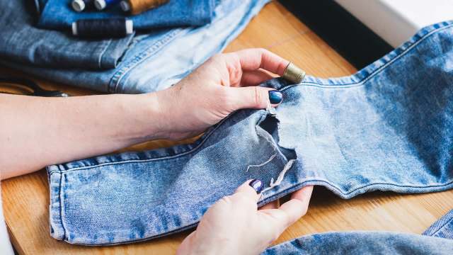 A person repairs torn jeans.