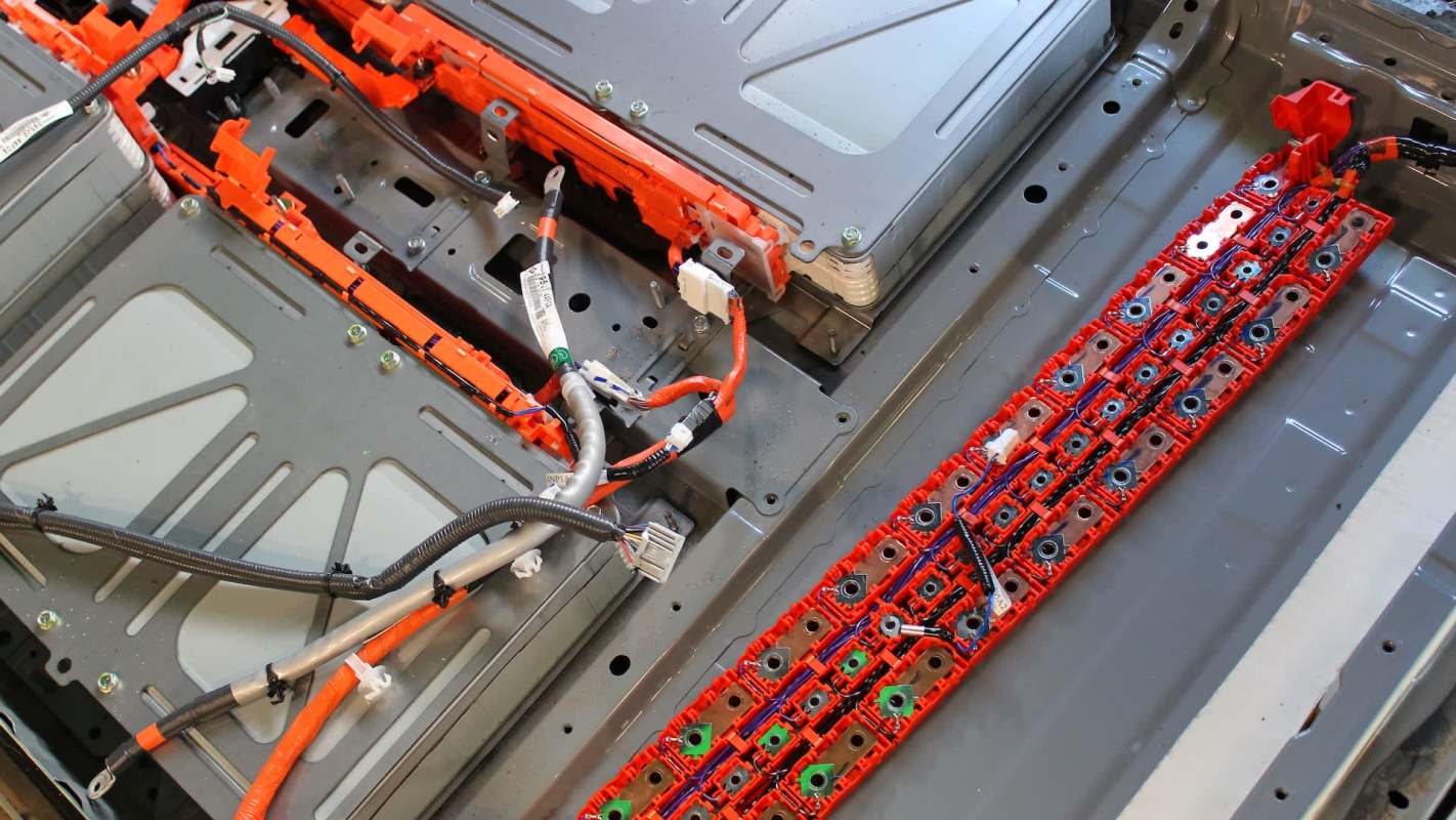 An open electric vehicle battery pack showing wires, connectors, and multiple battery cells.