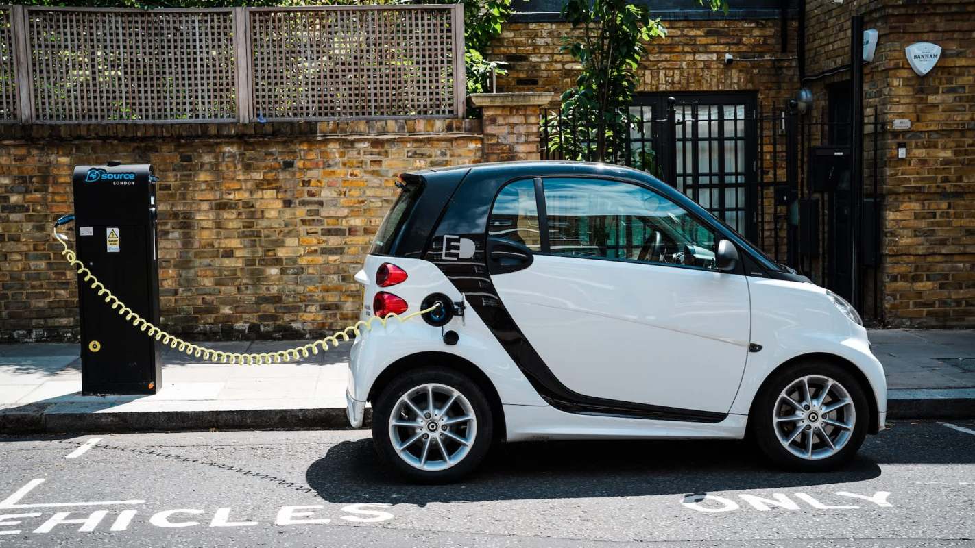 A white electric car charging at a station on a city street.