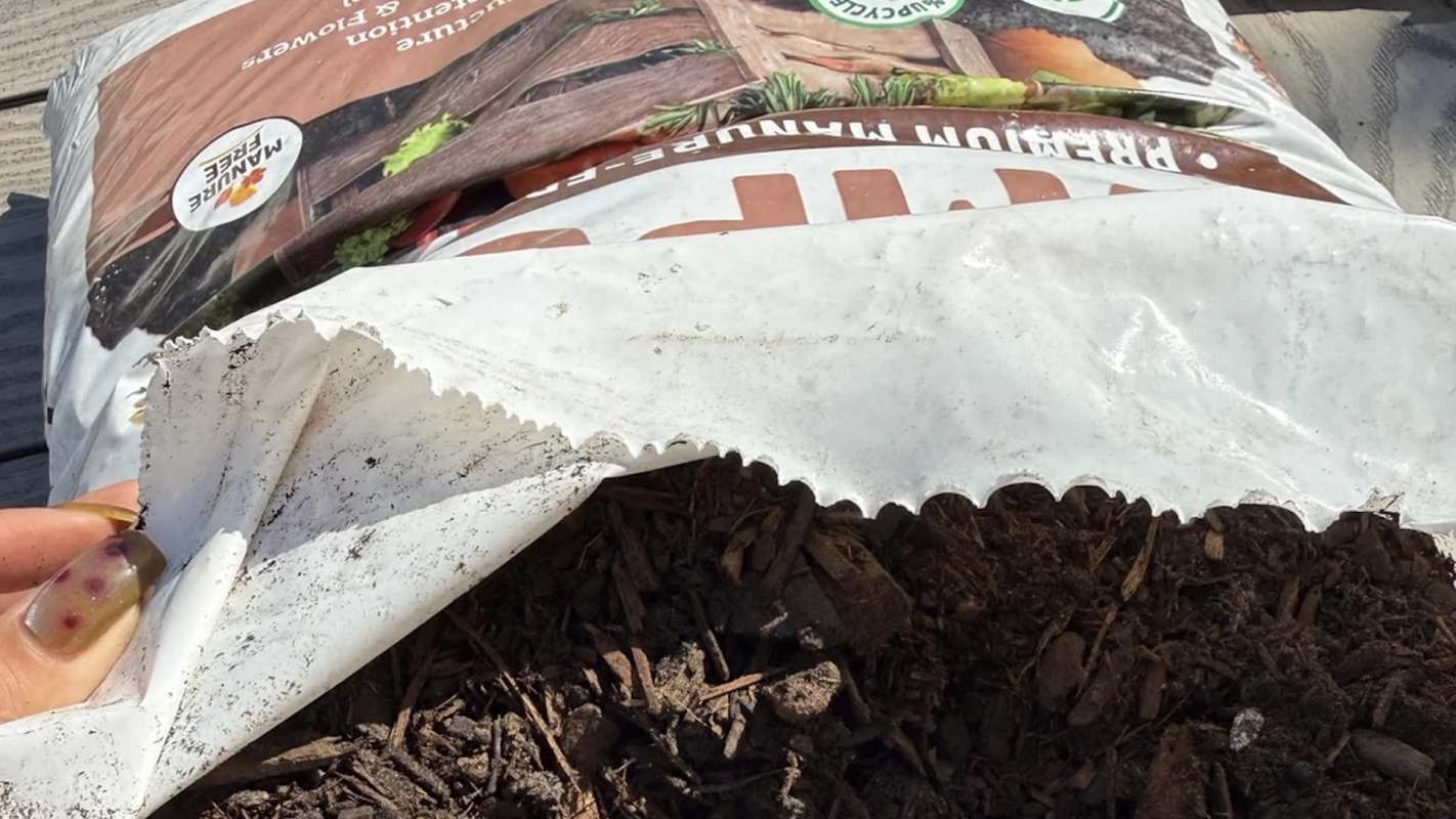 A close-up of a partially opened bag of mulch revealing dark, fibrous material inside.