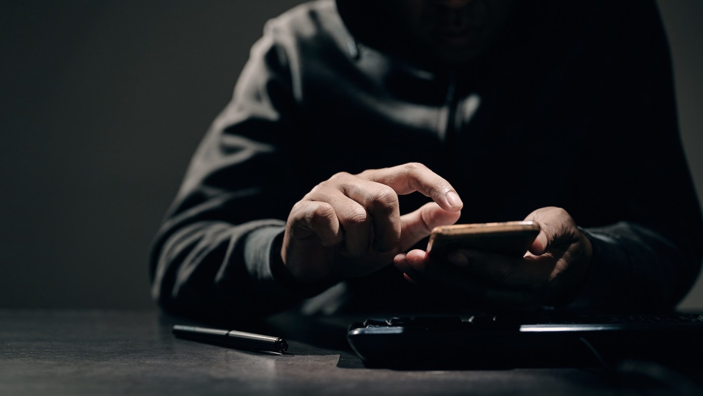 A person in a dimly lit room uses a smartphone.