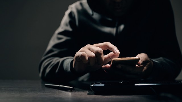 A person in a dimly lit room uses a smartphone.