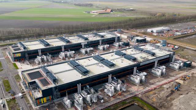 An aerial view of a modern industrial facility with multiple large buildings and surrounding green fields.