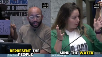 Two people speaking at a city council meeting, one holding a sign, focusing on environmental issues.
