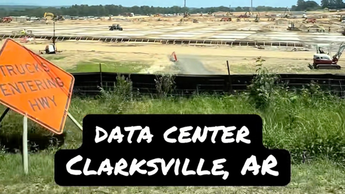 Construction site of a data center in Clarksville, AR, with a "Trucks Entering Hwy" warning sign in the foreground.