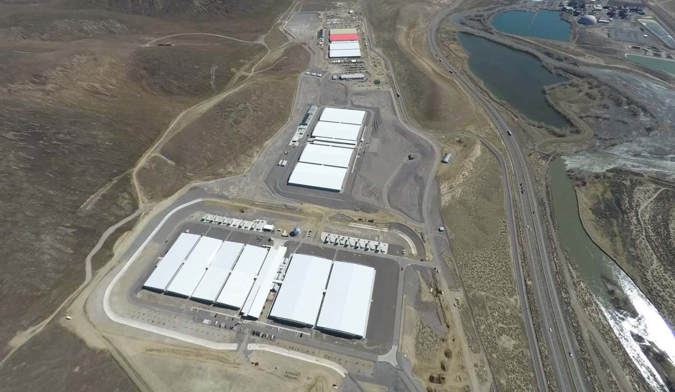An aerial view of a large industrial facility with white-roofed buildings.