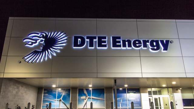 A well-lit DTE Energy sign with a stylized face logo is displayed on a modern building exterior at night.