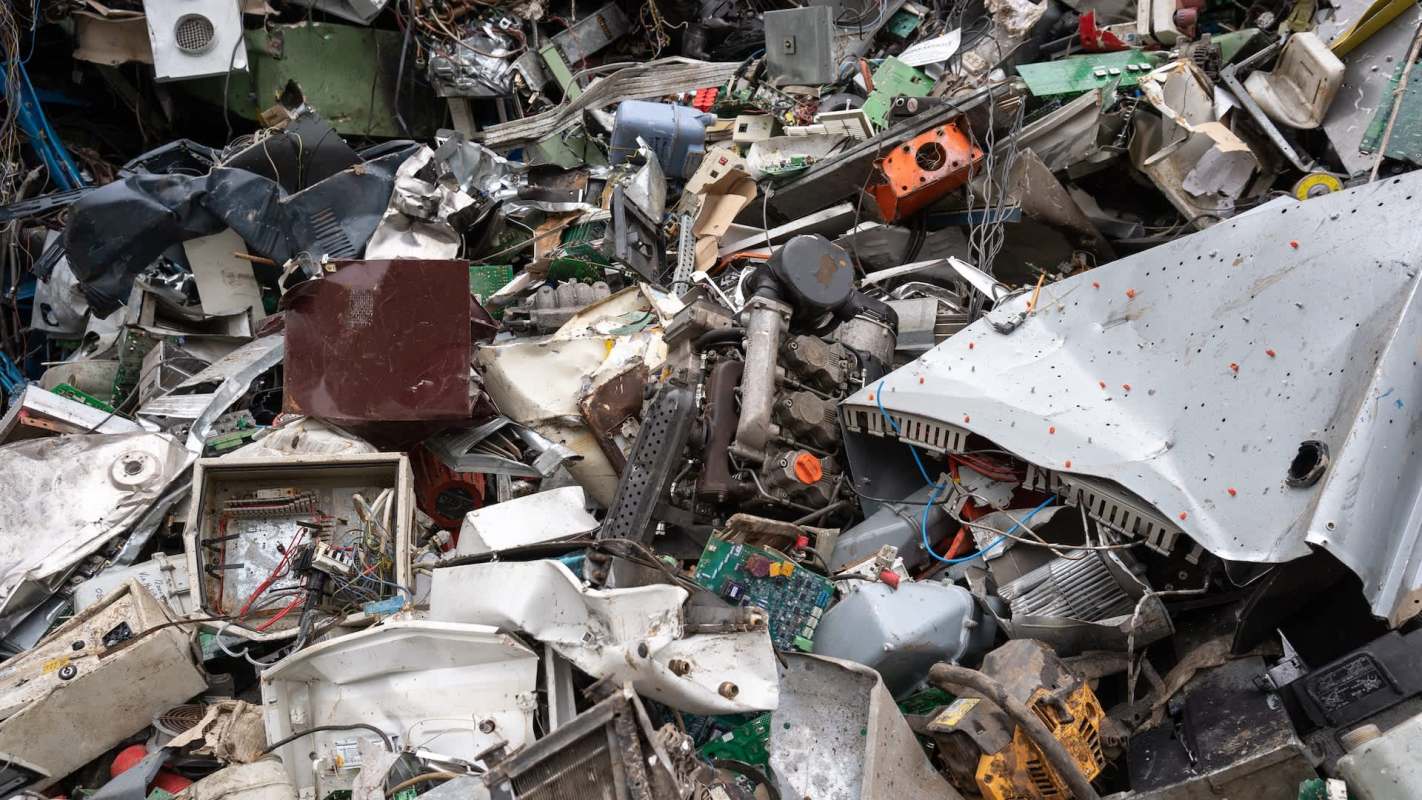 A pile of electronic waste and metal scraps in a junkyard.