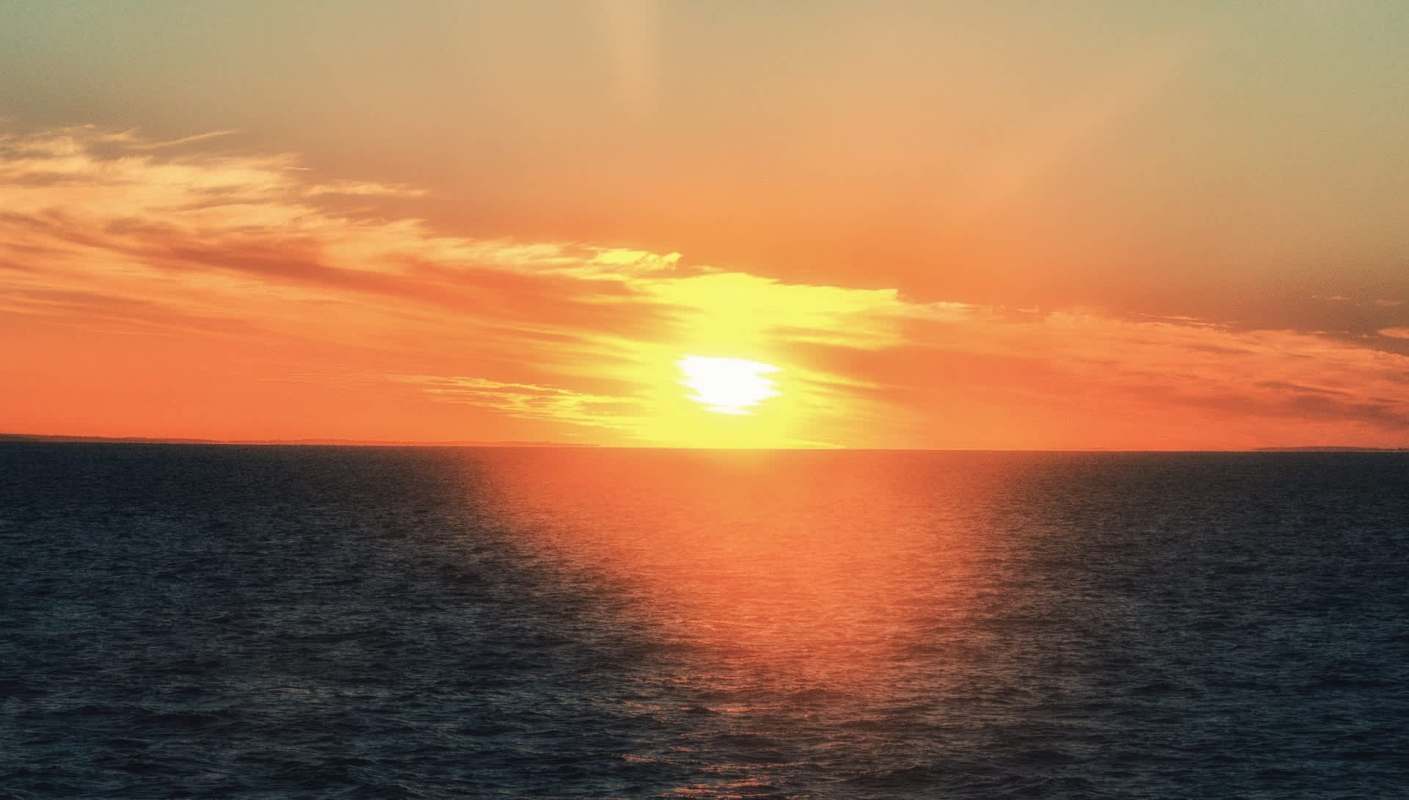 A vibrant sunset over the ocean, with warm hues of orange and yellow reflecting on the water.