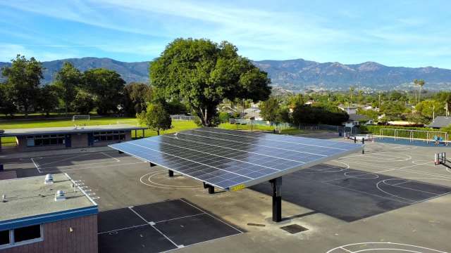 A solar panel structure over a elementary school playground.