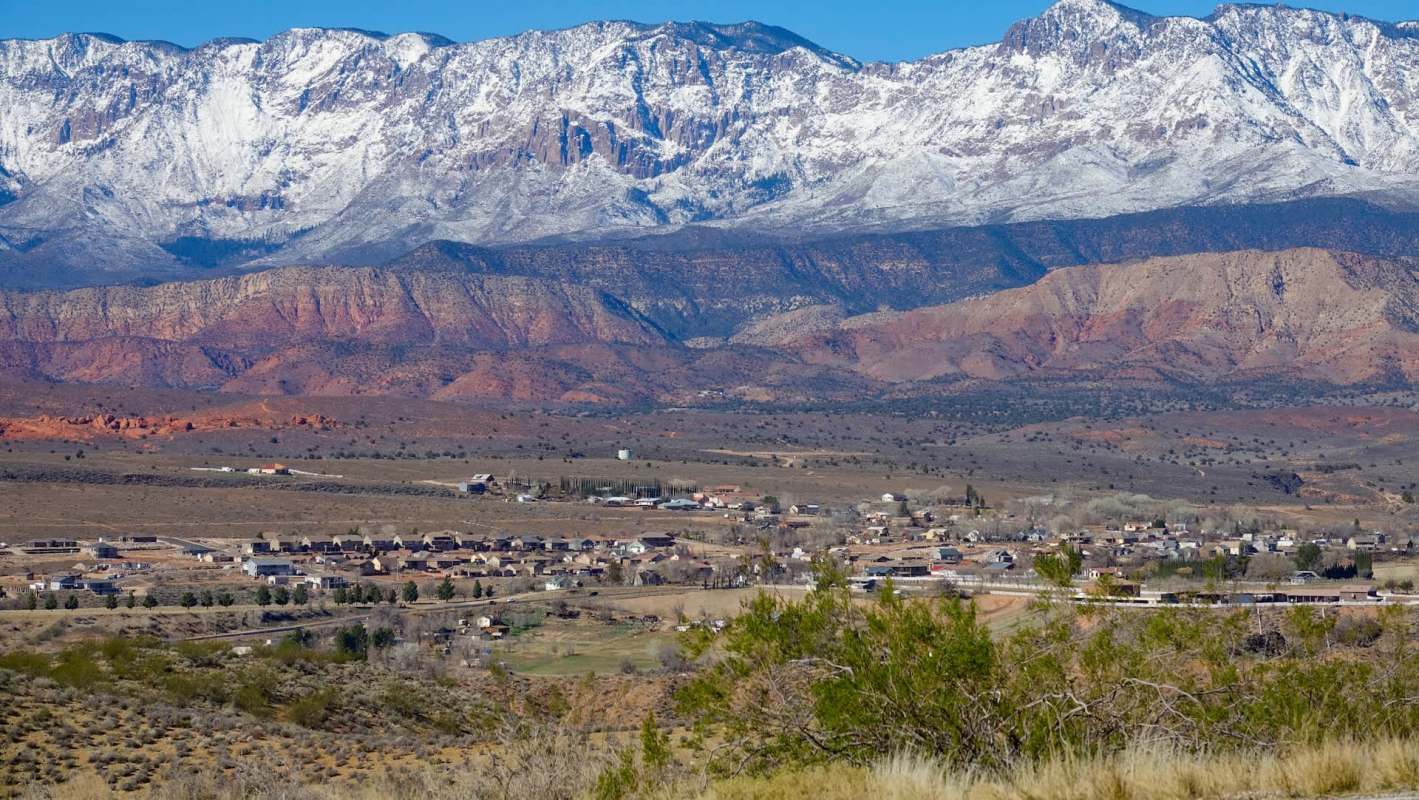 A small town in the foreground, with mountains in the background.