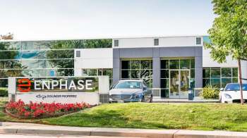 A modern office building with a prominent "Enphase" sign and parked cars, surrounded by landscaped greenery.