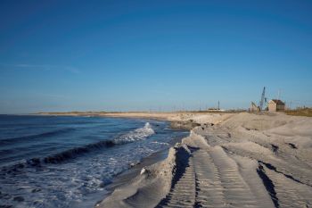 A beach stretches along the shore where there is erosion.