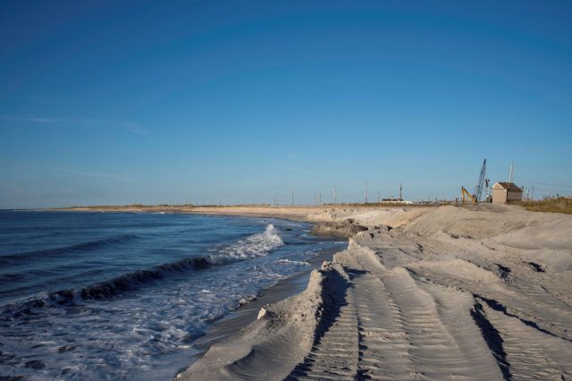 A beach stretches along the shore where there is erosion.