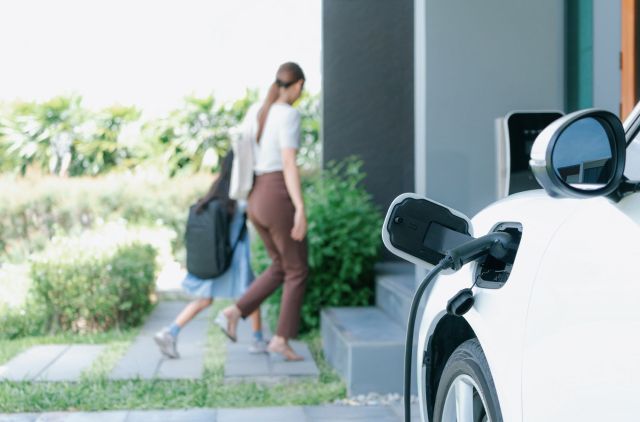 An EV charging while a parent and child enter a home.