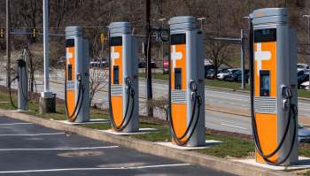 A row of electric vehicle chargers next to a highway.
