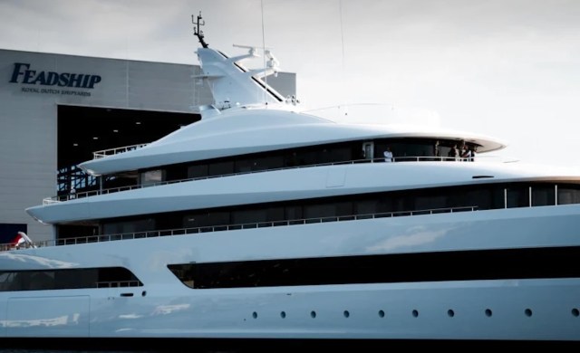 A superyacht docked near a sign reading "Feadship Royal Dutch Shipyards."