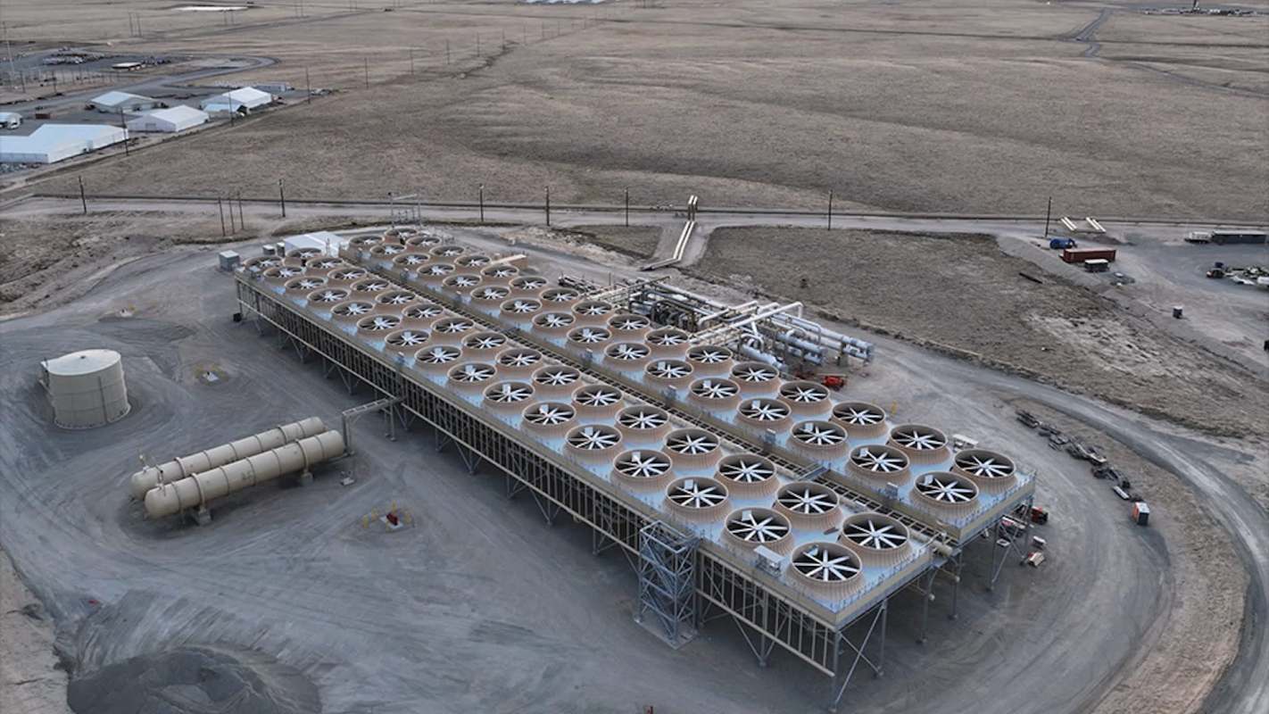 A large industrial facility with numerous cooling towers, set against a barren landscape.