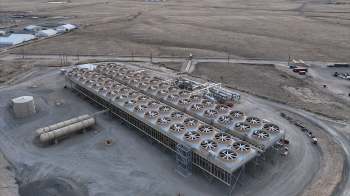 A large industrial facility with numerous cooling towers, set against a barren landscape.