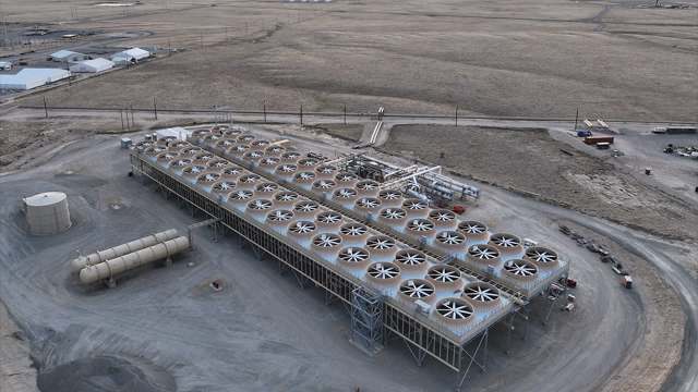 A large industrial facility with numerous cooling towers, set against a barren landscape.