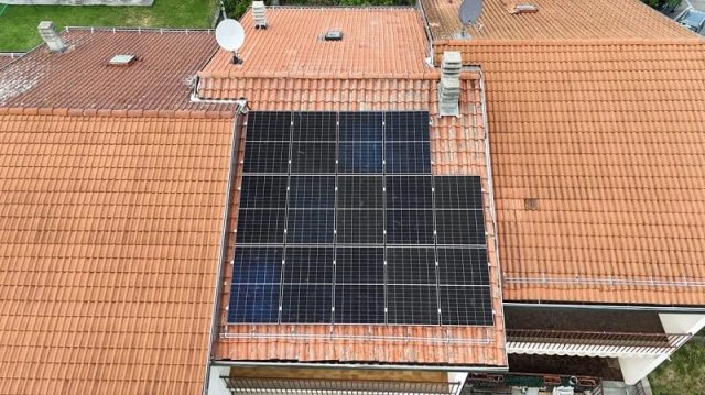 A rooftop covered with solar panels on traditional tile roofing.