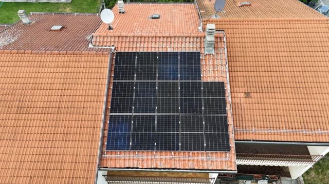 A rooftop covered with solar panels on traditional tile roofing.