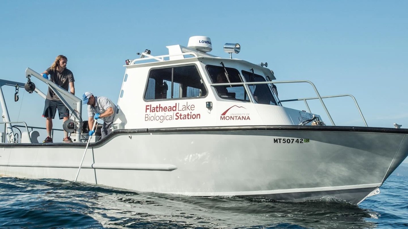 Two researchers work on a boat marked "Flathead Lake Biological Station."