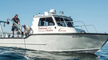 Two researchers work on a boat marked "Flathead Lake Biological Station."