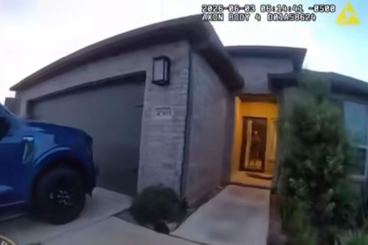 Police body cam footage of a blue truck parked in front of a residential house with a person standing in the doorway.