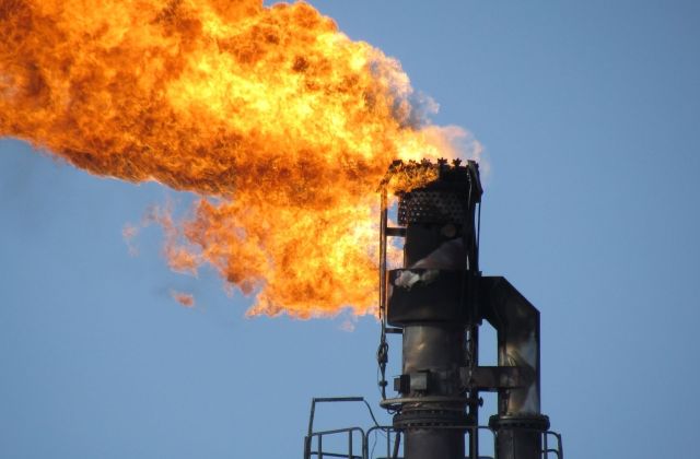 A flame burns at the top of an industrial flare stack.