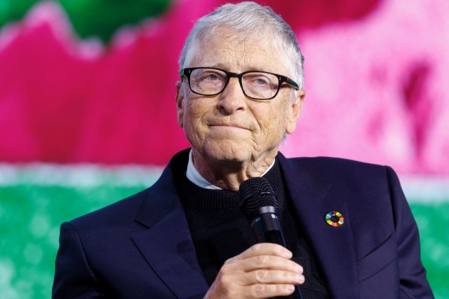 Bill Gates in a dark suit speaking into a microphone.