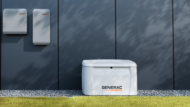 A white Generac backup generator and two wall-mounted battery units against a dark wall.