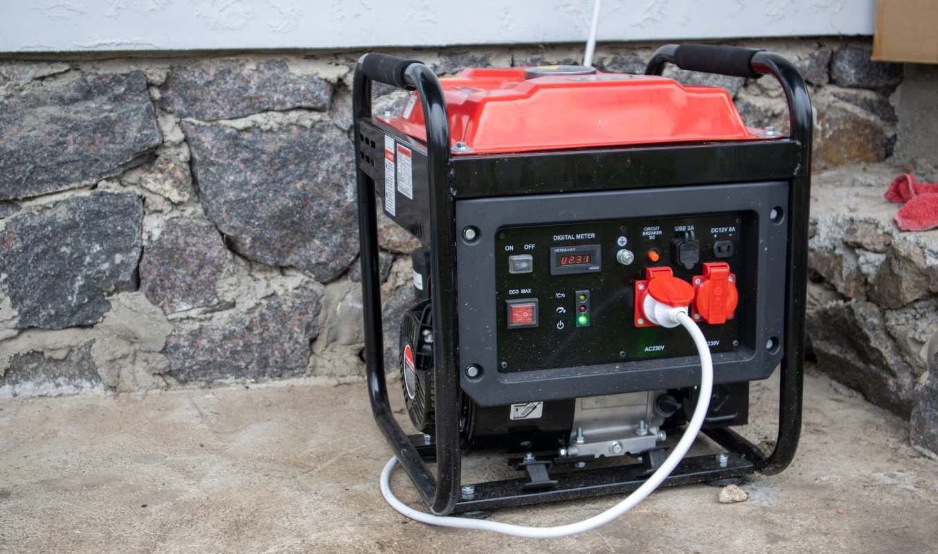 A portable generator against a stone wall.
