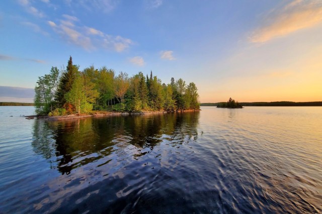 A small island of forest land in the middle of a lake.