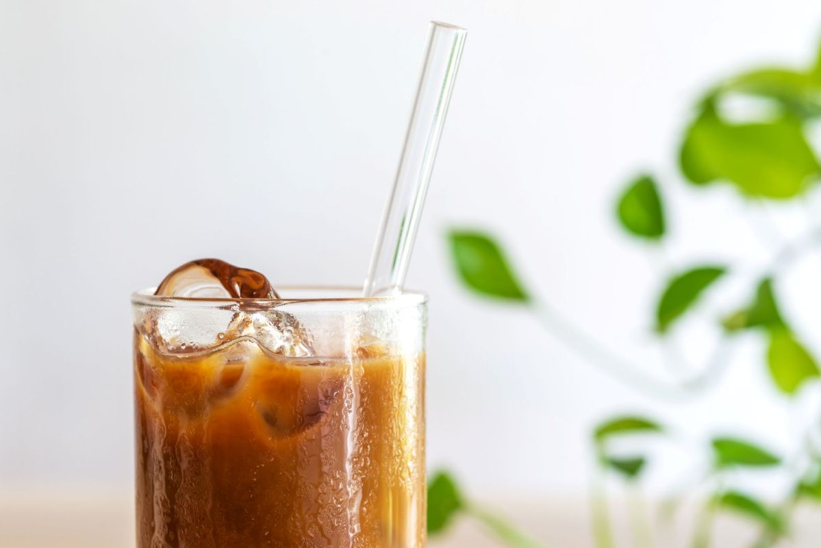A glass of iced coffee with a glass straw.