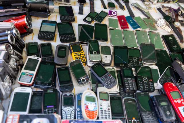 A variety of used mobile phones and devices displayed on a table.