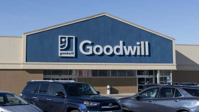 A Goodwill store front with a blue exterior and the logo prominently displayed, surrounded by parked cars.