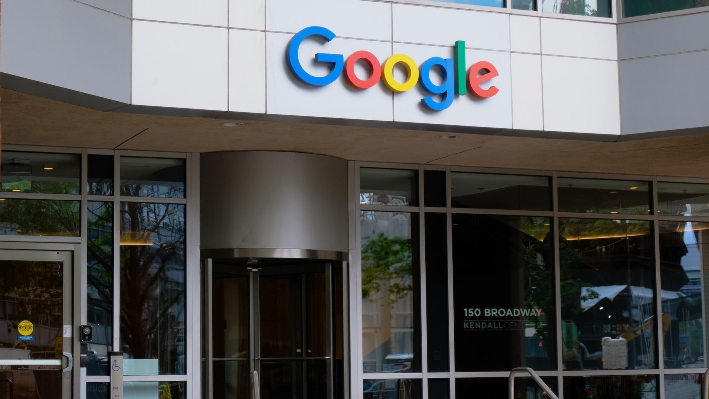 Google's colorful logo displayed above the entrance of a modern building with large glass windows.