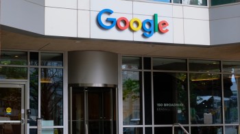 Google's colorful logo displayed above the entrance of a modern building with large glass windows.