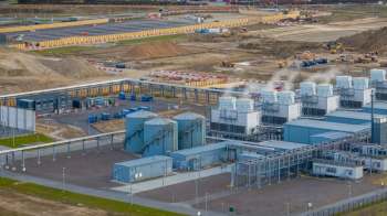 An industrial area with large storage silos, machinery, and construction activity.