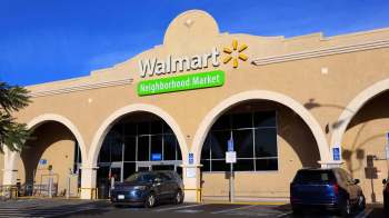 A Walmart Neighborhood Market building with prominent signage and vehicles parked in front.
