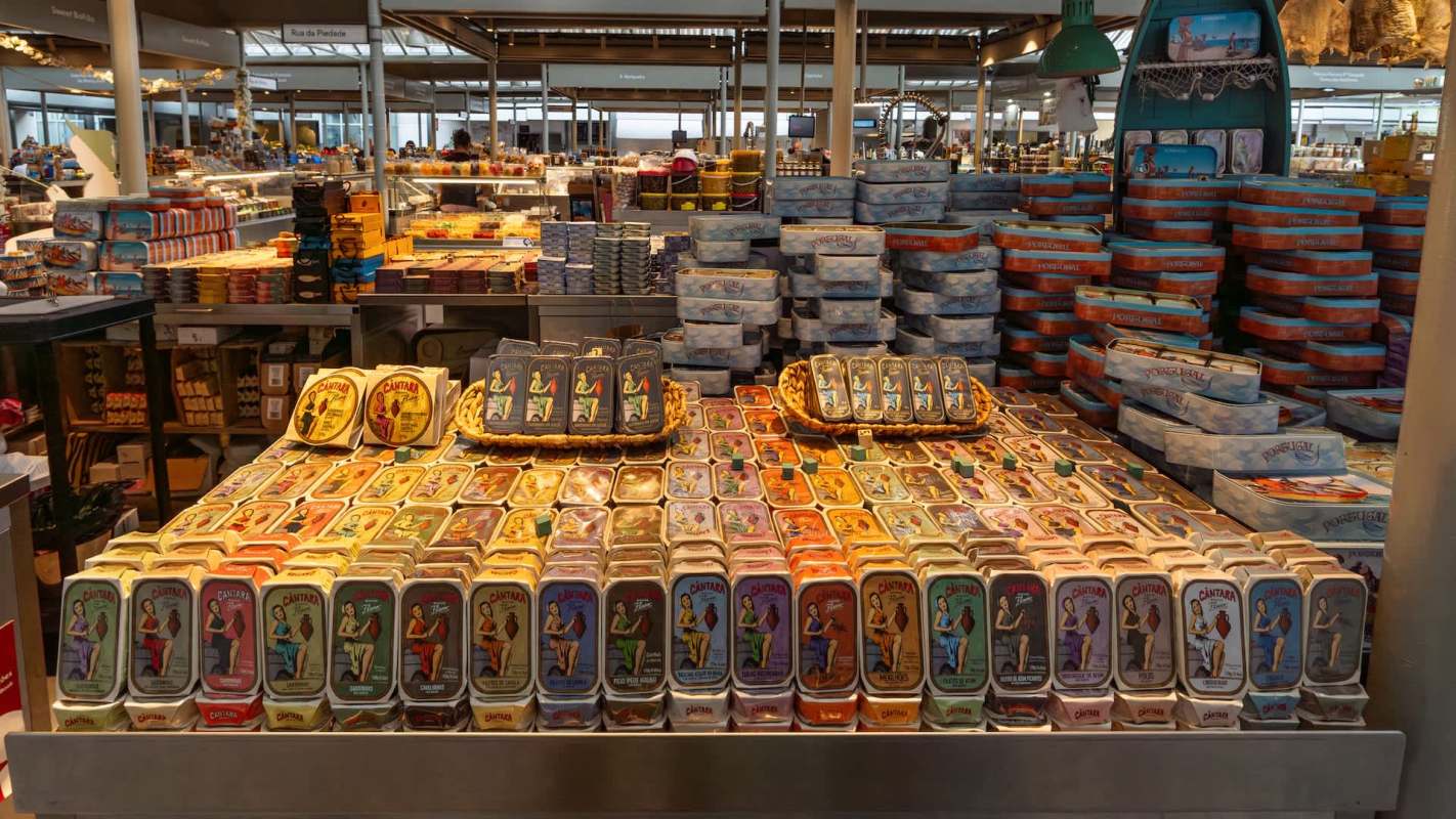 A display of canned fish with artistic labels at a market.