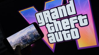 A game trailer playing on a smartphone in front of a Grand Theft Auto logo.