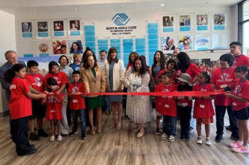 A group of children and adults participate in a ribbon-cutting ceremony at the Boys & Girls Club.