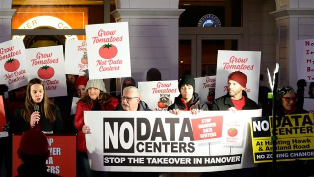 A group of protesters holding signs reading "Grow Tomatoes, Not Data Centers" at a public rally.